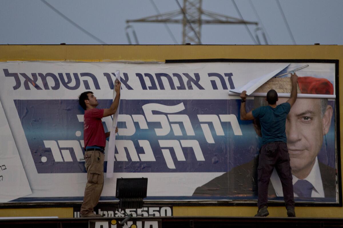Workers remove a campaign billboard of the Likud party showing Prime Minister Benjamin Netanyahu, in Ramat Gan, Israel, on March 18.