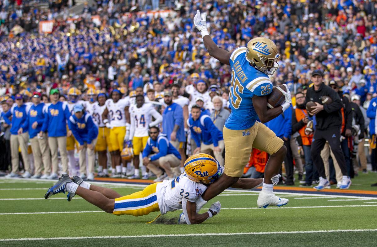 UCLA running back T.J. Harden breaks the tackle of Pittsburgh defensive back P.J. O'Brien to score a touchdown.