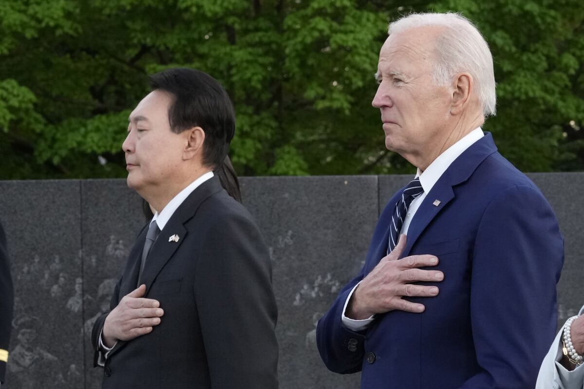 President Joe Biden and South Korea's President Yoon Suk Yeol in business suits with their hands over their hearts.