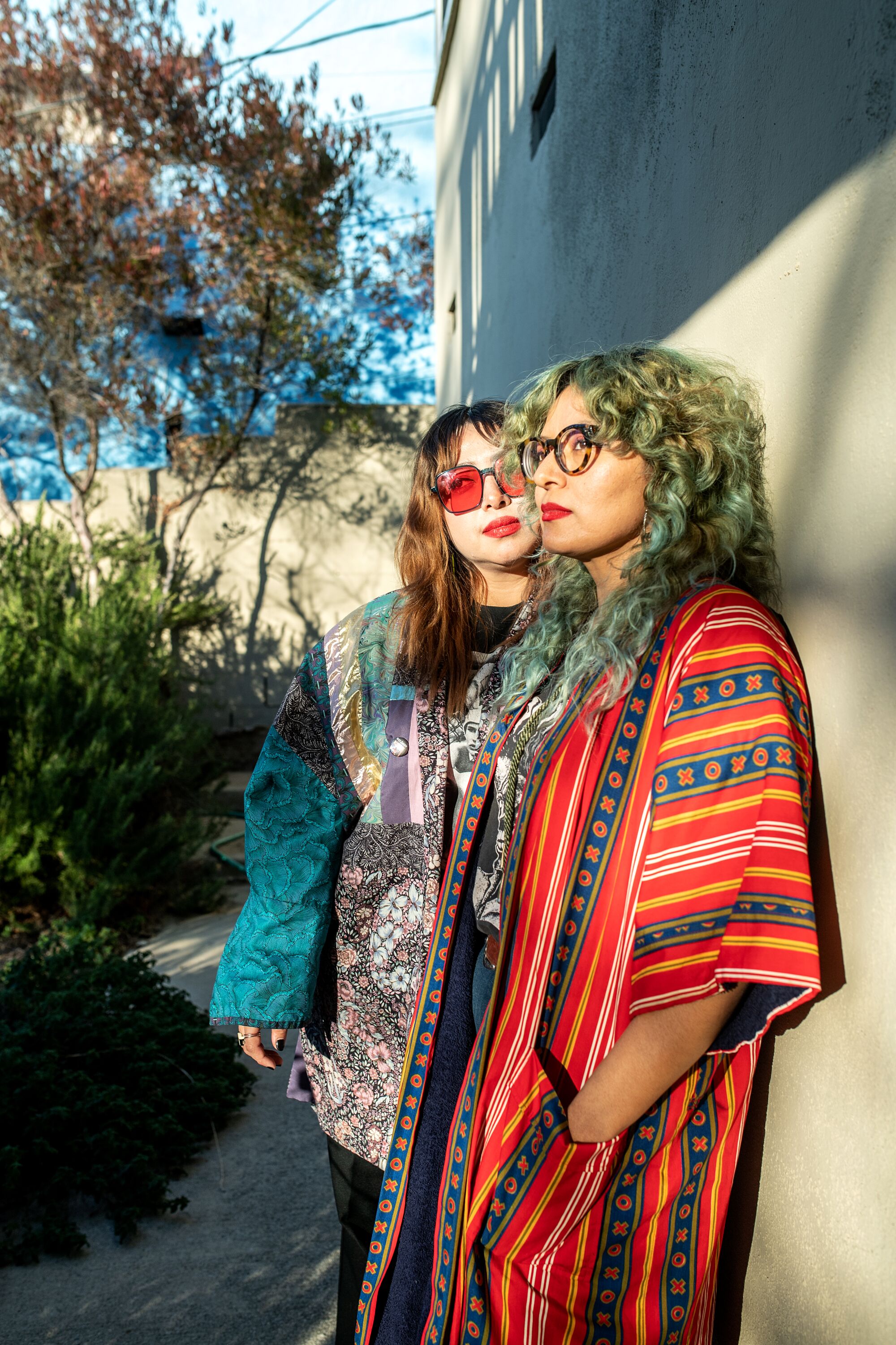 Rebecca and Ursula Recinos lean against a sun-kissed wall.