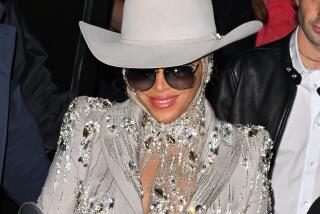 Beyonce wears a large white cowboy hat, sunglasses anda jeweled blazer to a fashion show