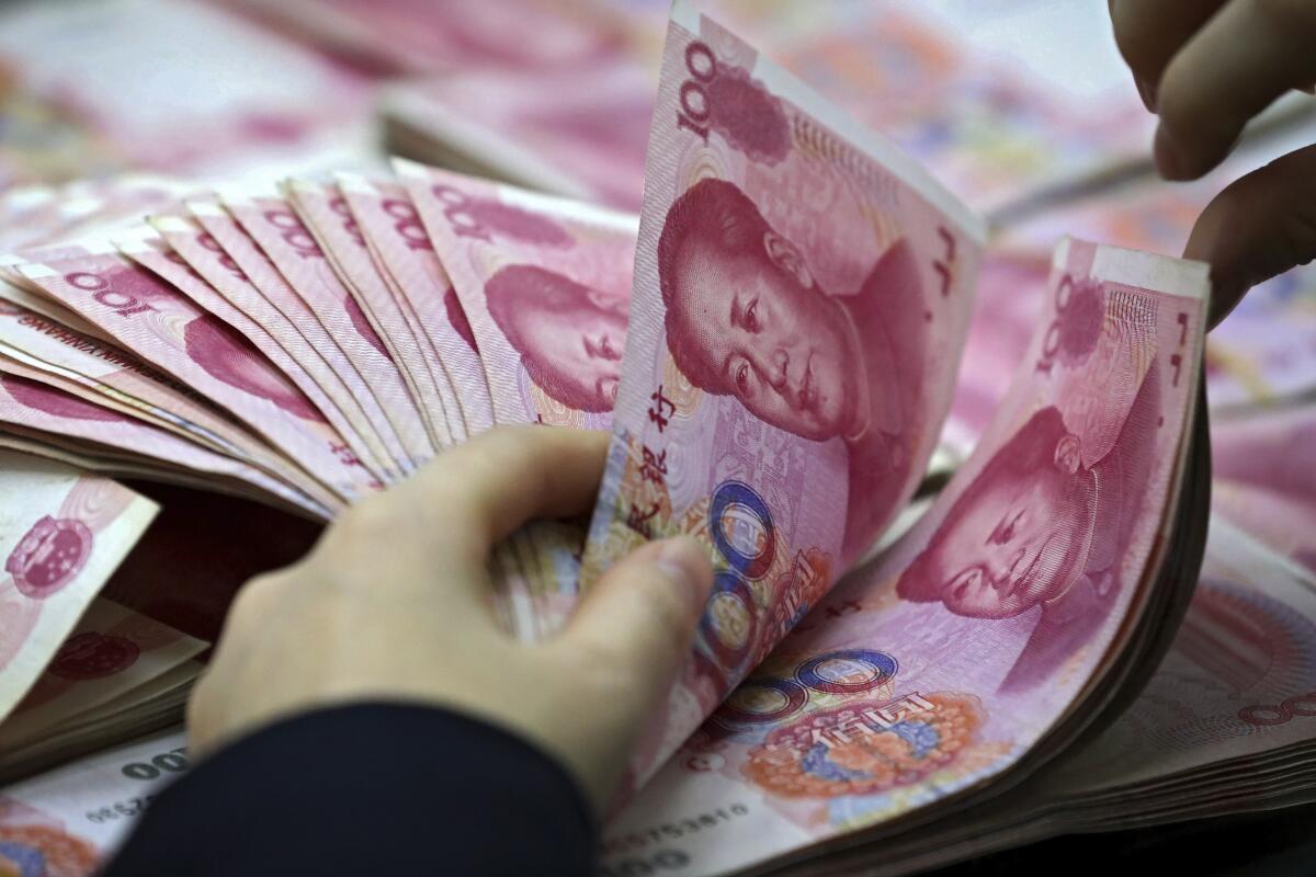 Un trabajador cuenta billetes de la divisa china.