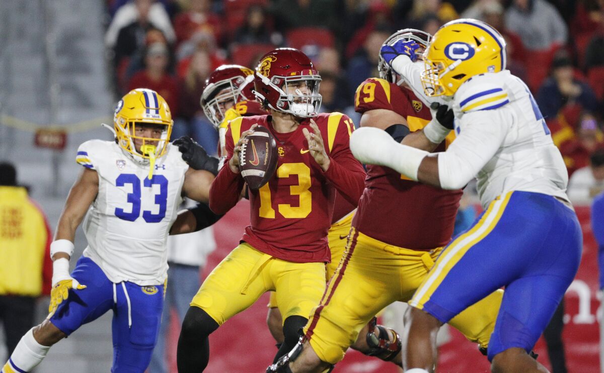 USC quarterback Caleb Williams holds the ball while surrounded by opponents.