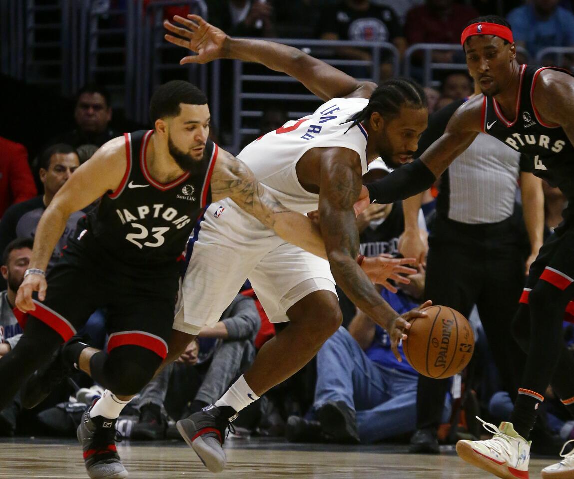 Clippers forward Kawhi Leonard tries to split the defense of Raptors Fred Vanvleet, left, and Rondae Hollis-Jefferson during the fourth quarter of a game Nov. 11 at Staples Center.