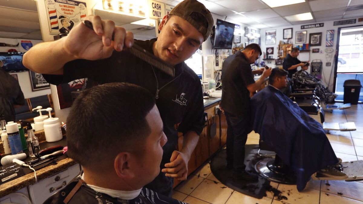 Osbaldo Prieto gives a haircut to Stephen Juarez at Tony's Barbershop in Delano. Prieto gave free haircuts to some of the children of Santos Hilario Garcia and Marcelina Garcia Profecto.