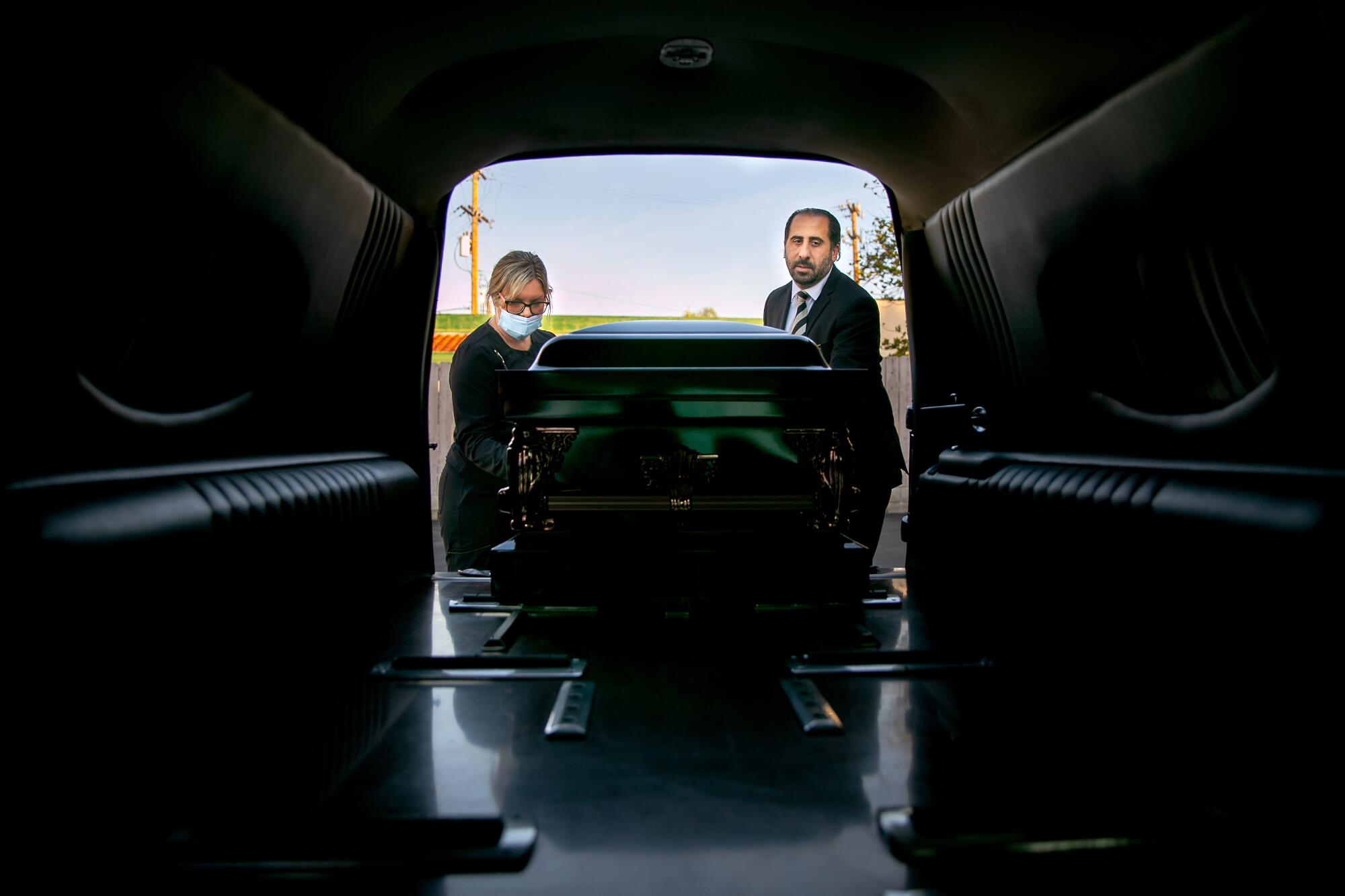 Kristy Oliver and Robert Zakar load a casket.