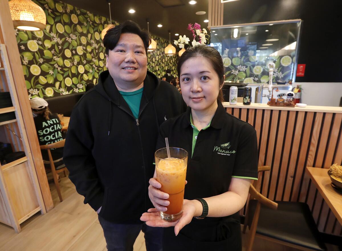 Owner Kanate Ungkasrithongkul and wife Anita Lin stand inside their traditional Thai restaurant.