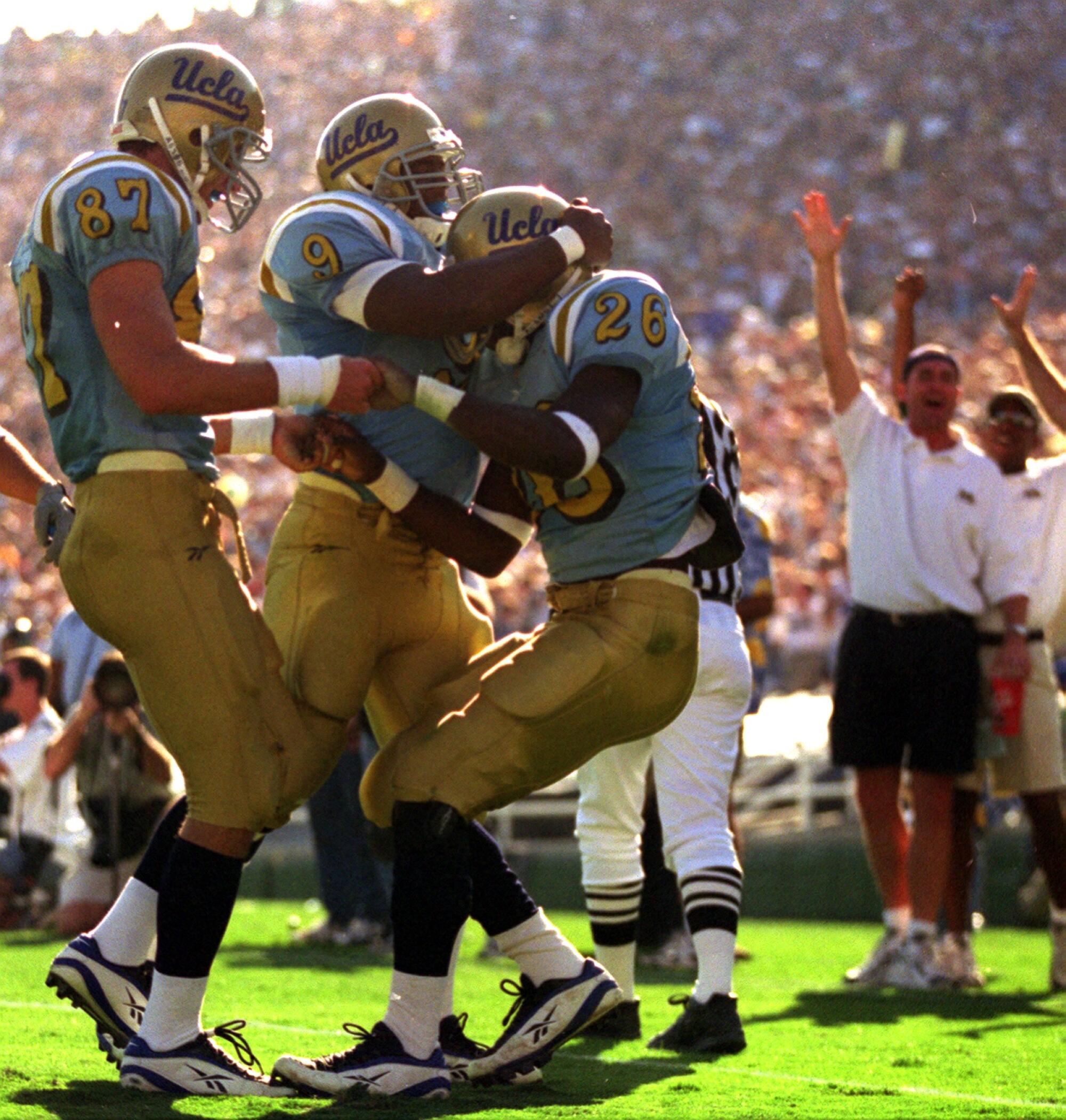 UCLA'S running back DeShaun Foster (26) is mobbed by teammates Durell Price (9) and Danny Farmer after scoring