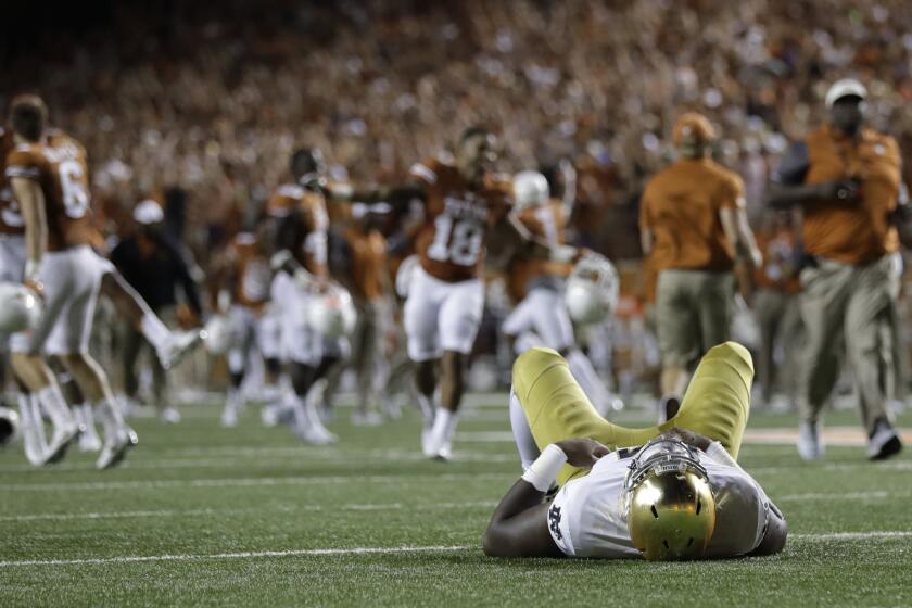 A Notre Dame player lies on the turf as Texas celebrates their win in double overtime in Austin, Texas.