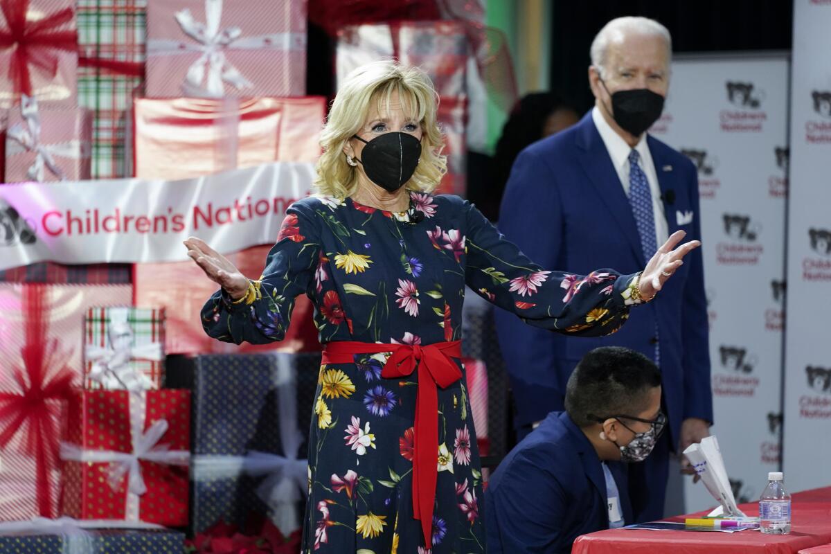 The president, in a blue suit, and first lady, in a floral dress, enter a festively decorated area.