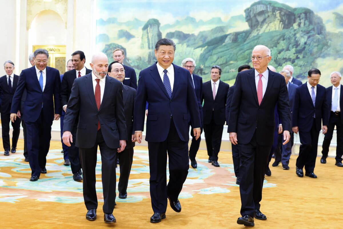 Chinese President Xi Jinping, center, walks through a large ornate room with a group of men.