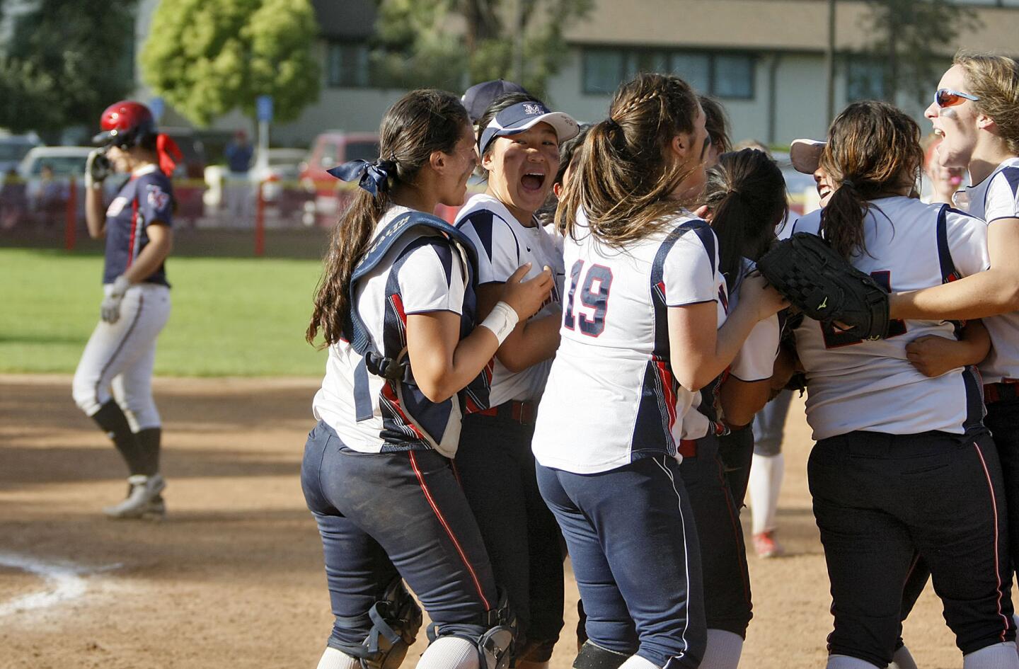 As a dejected La Salle softball player walks off the field in the background, Maranatha softball players celebrate their away win vs. La Salle at Latter Day Saints softball field in Pasadena on Thursday, April 11, 2013.