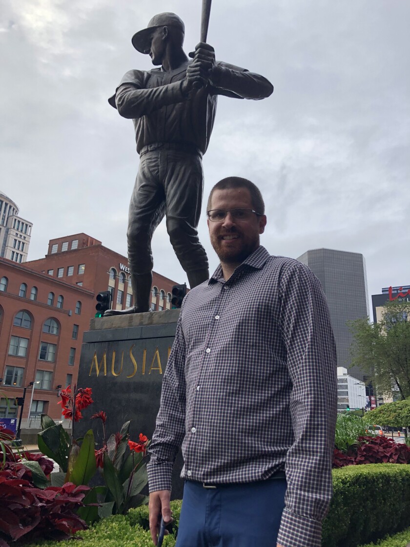 St. Louis Cardinals fan Joe Schwarz stands next to a statue of Cardinals legend Stan Musial outside of Busch Stadium.