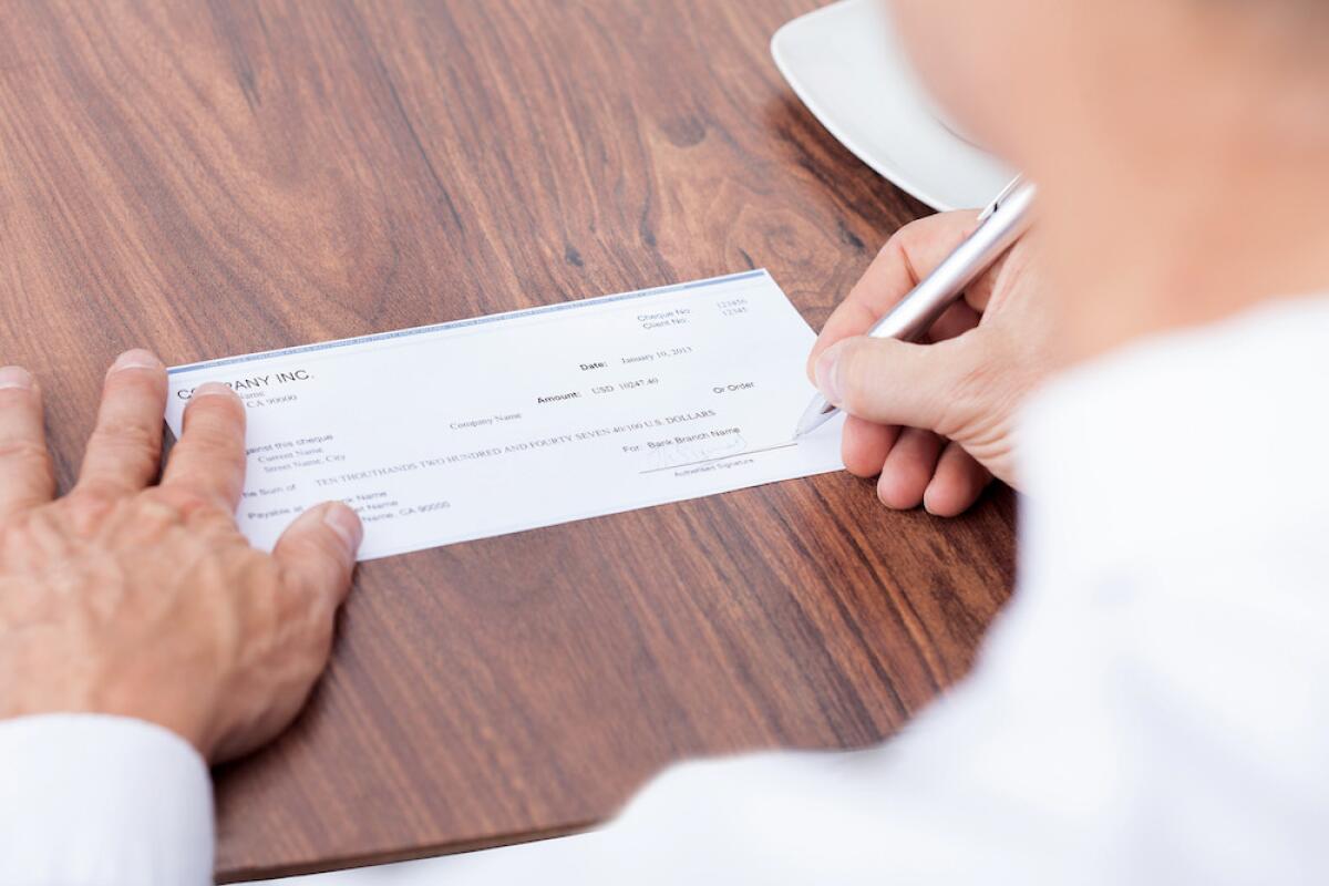 A man's hands are shown writing a check.