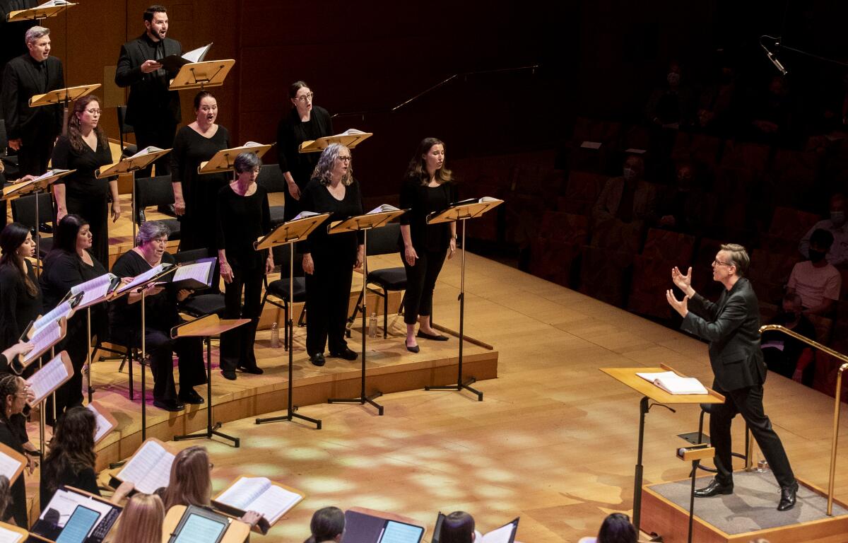 A conductor gestures toward singers onstage at Walt Disney Concert Hall
