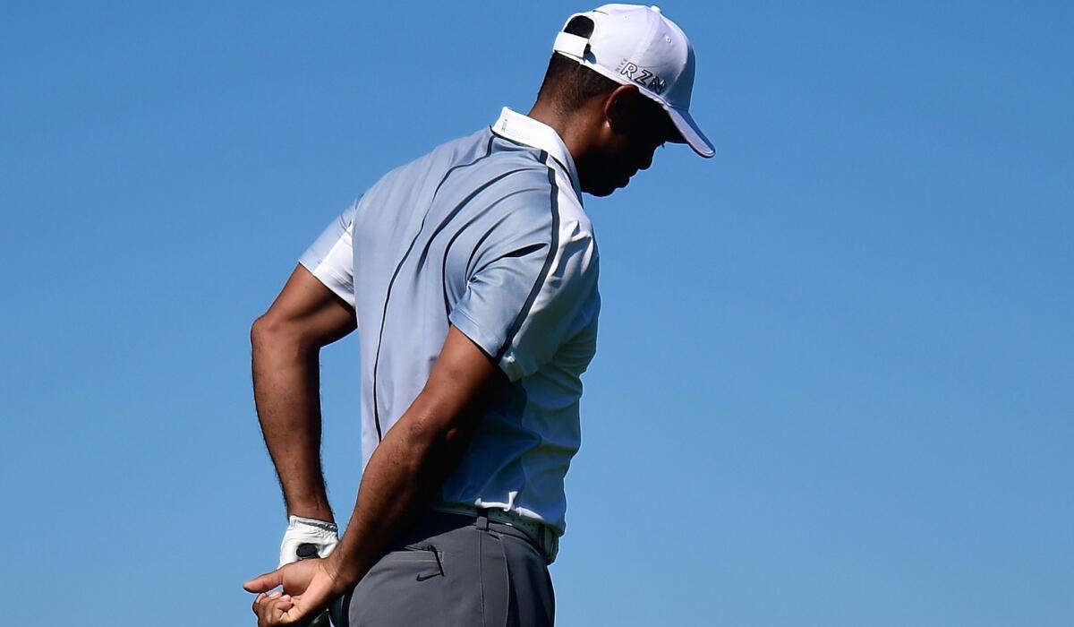 Tiger Woods holds his back after hitting his tee shot at No. 15 on Thursday during the first round of the Farmers Insurance Open at Torrey Pines.