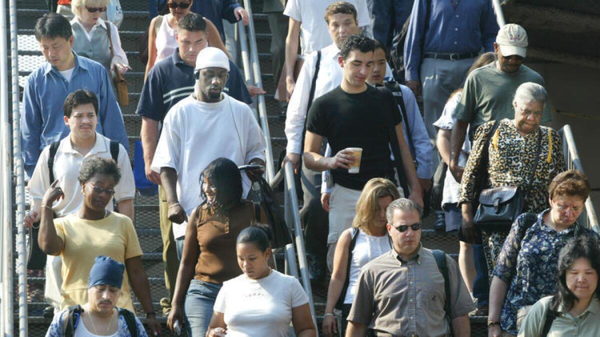Camino sus empleos en la ciudad de Nueva York, los trabajadores que conmutan diariamente descienden los escalones del ferry de Staten Island.