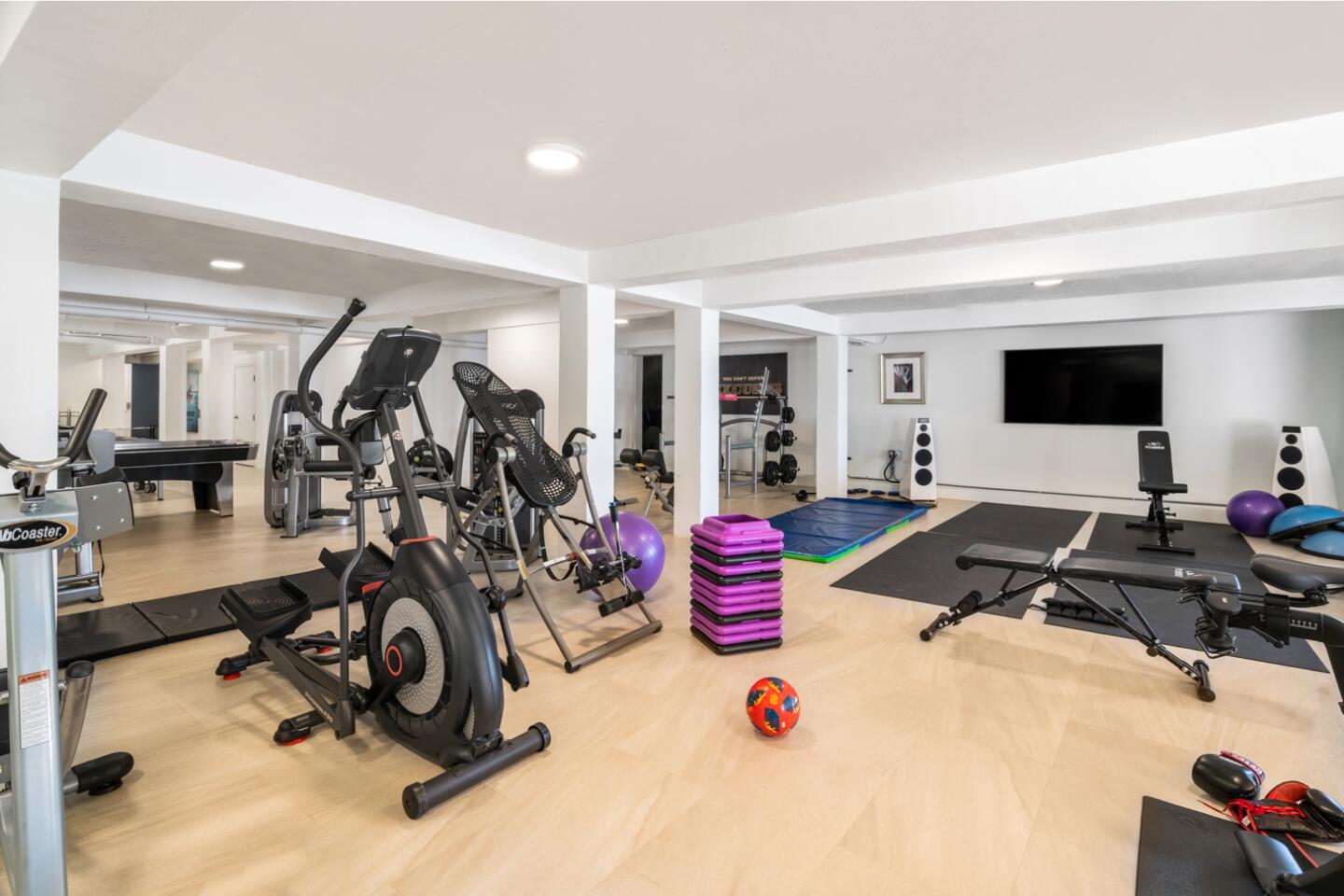 A workout room is spacious with mirrored walls.