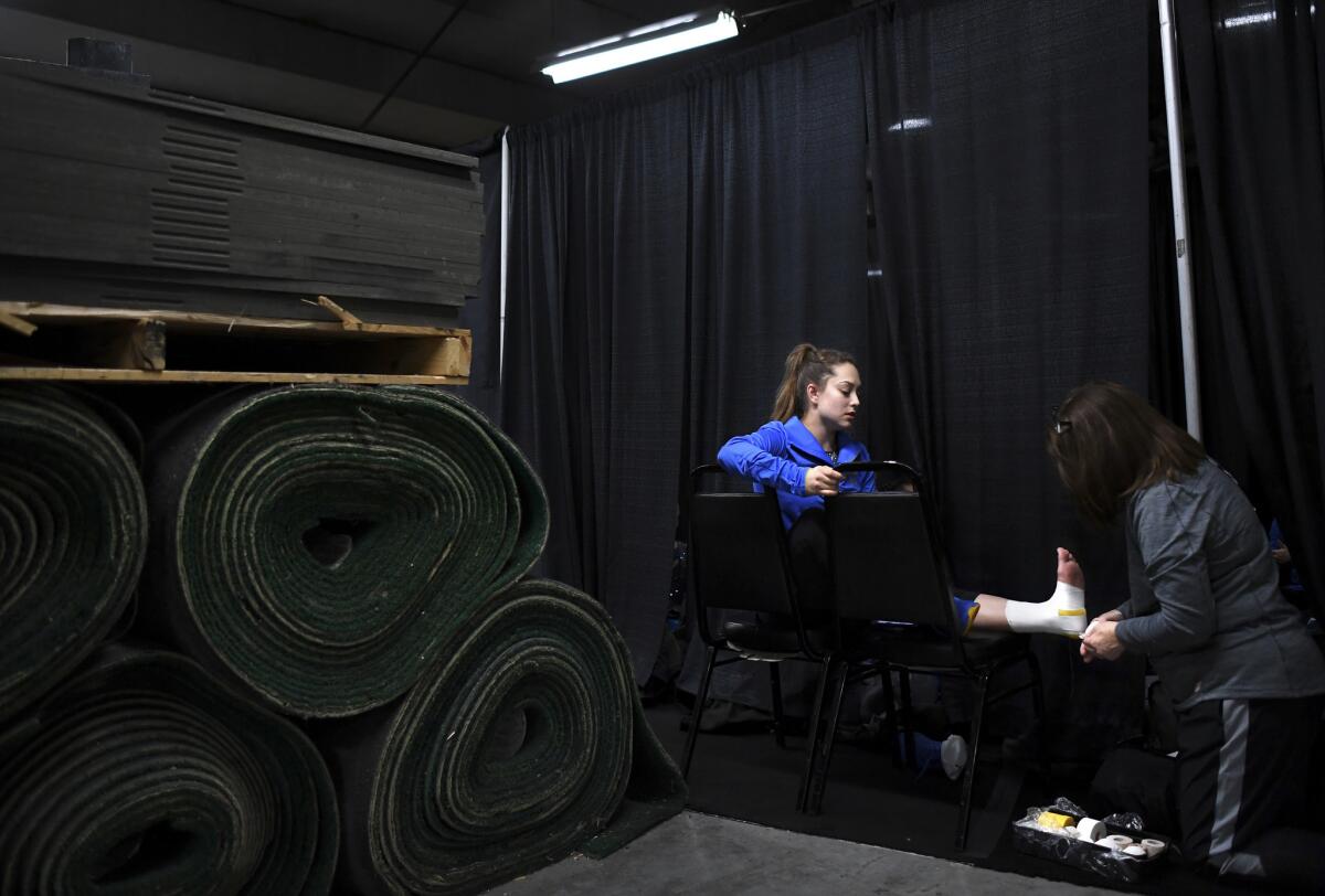 UCLA gymnast Kendall Poston has her foot taped outside the locker room before the Pac-12 Championships in Salt Lake City.