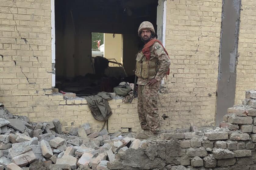 An army soldier examines damages on the site of a bombing at a police station on the outskirts of Dera Ismail Khan, Pakistan, Tuesday, Dec. 12, 2023. A suicide bomber detonated his explosive-laden vehicle at a police station's main gate in northwest Pakistan on Tuesday, killing several policemen and wounding more than dozen others, officials said. Some militants also opened fire and a shootout between them and security forces was still ongoing, police officer Kamal Khan said. (AP Photo)