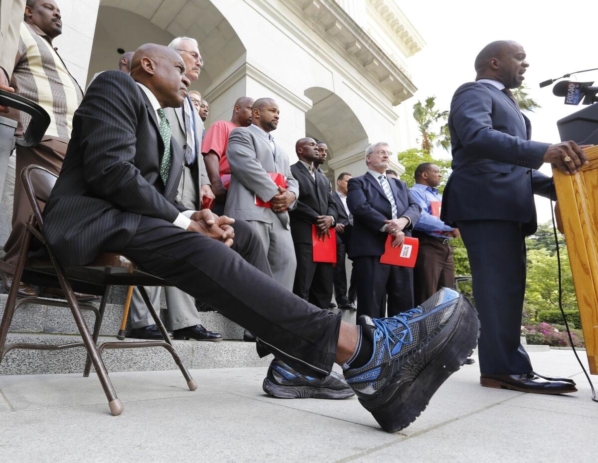 Former NFL linebacker Reggie Williams stretches his surgically repaired leg out as he listens to NFL Players Assn. executive director DeMaurice Smith speak in Sacramento back in April.
