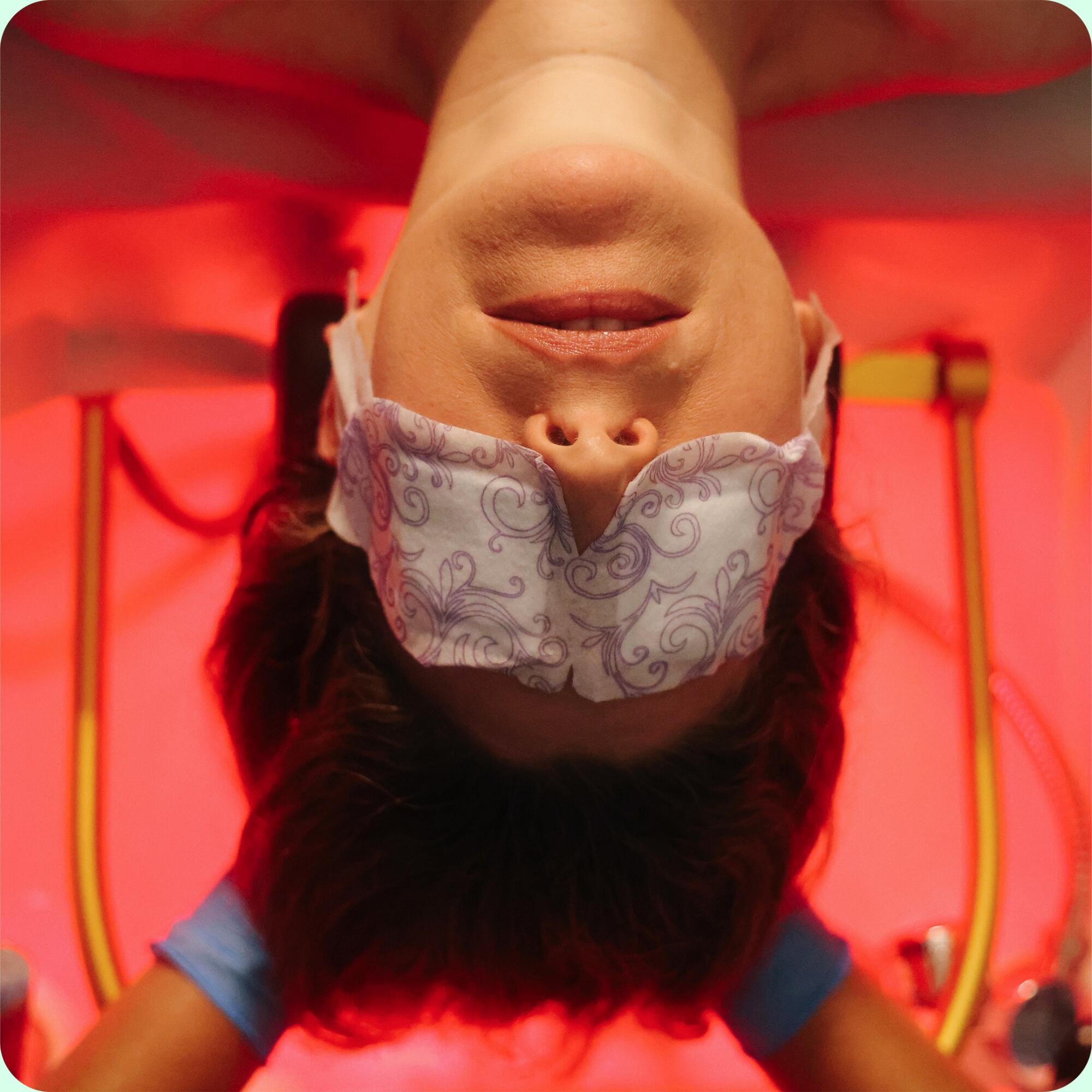 A woman leans back into a tub of water while wearing an eye mask.