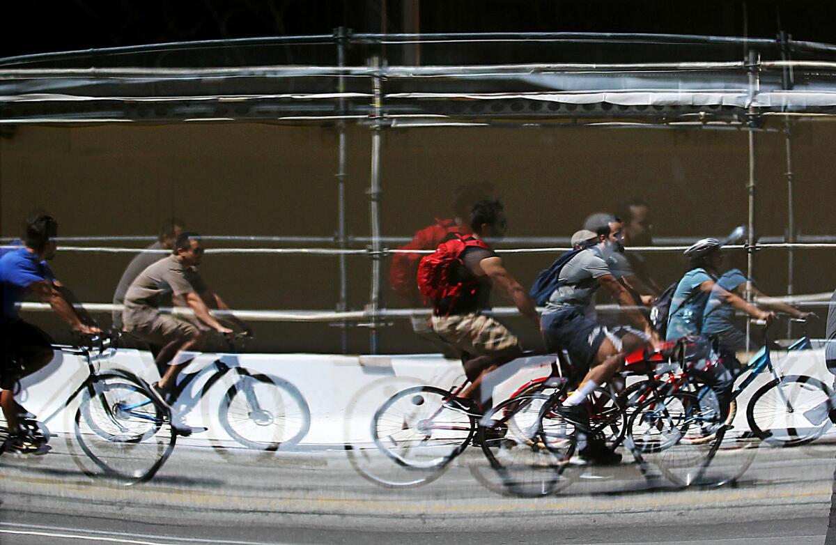 Bicyclists are reflected in the windows of a restaurant along Wilshire Boulevard in Los Angeles during the May 2009 CicLAvia festival.