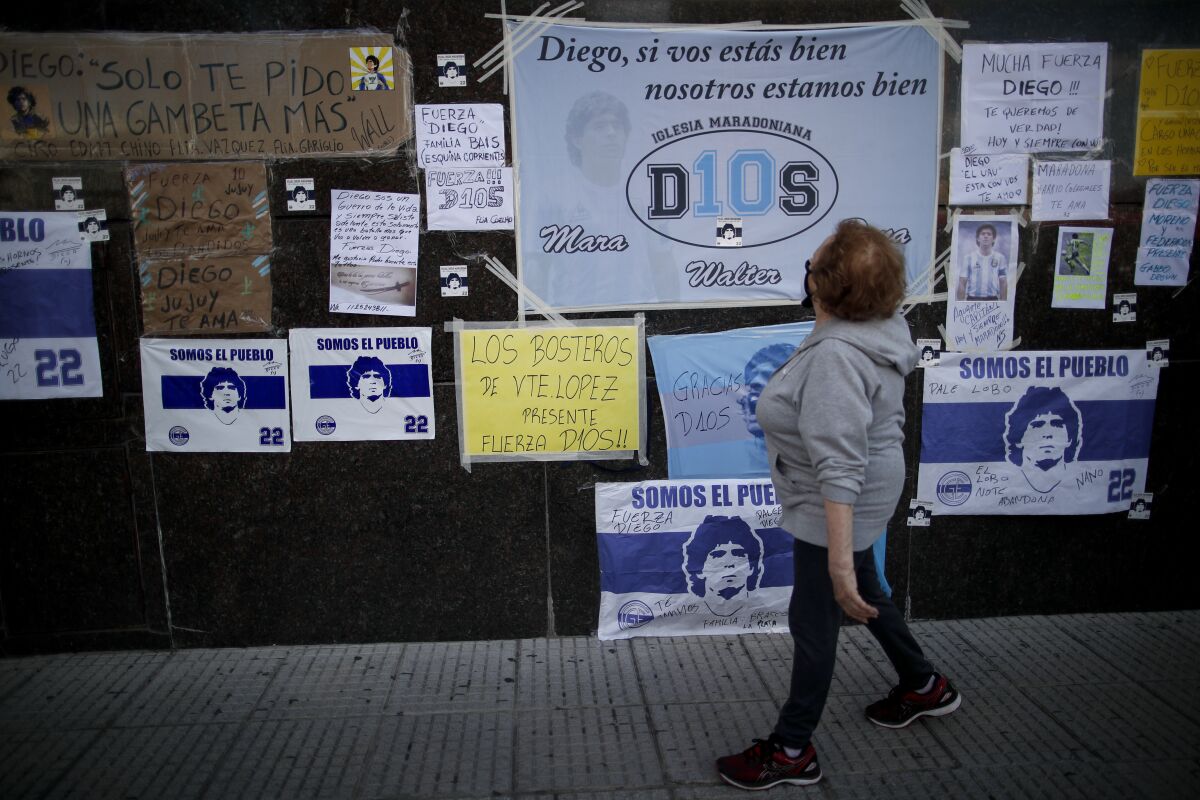 Una mujer observa un muro con mensajes de aliento a Diego Maradona 