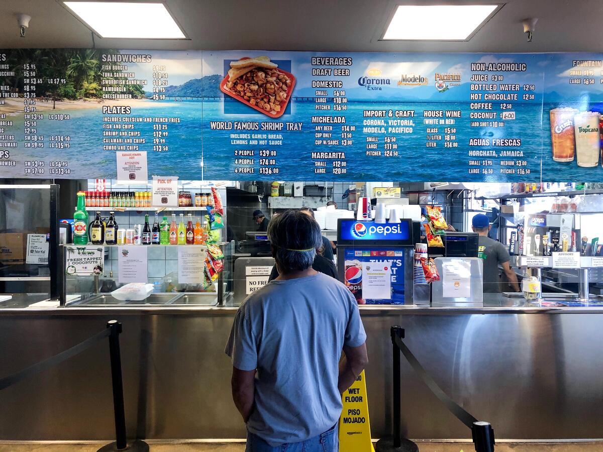 A customer waits in line to order takeout at San Pedro Fish Market.