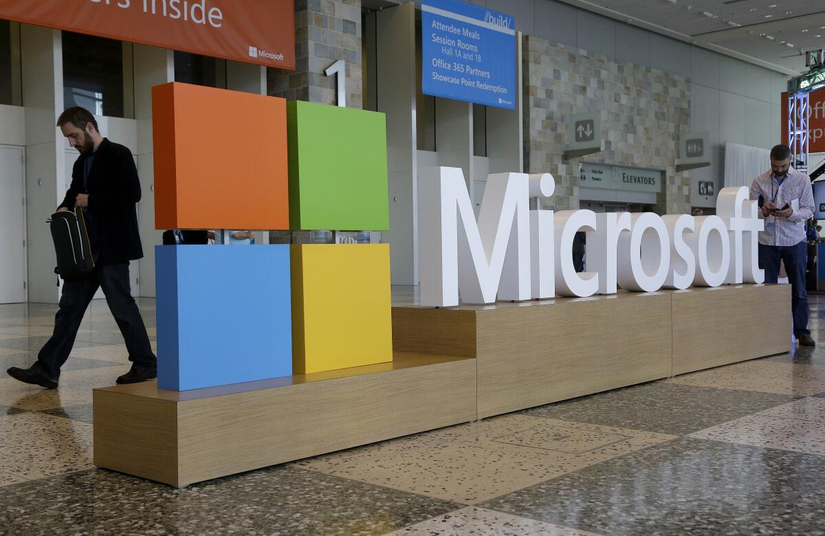 A person walks past a freestanding Microsoft logo