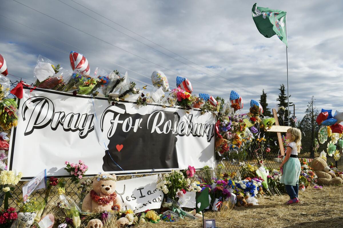 Bayleigh Case, of Roseburg, Ore., in October visits a makeshift memorial near the campus of Umpqua Community College Campus, scene of one of this year's mass shootings in the U.S.