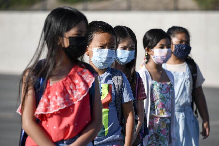 Masked students wait to be taken to their classrooms at Enrique S. Camarena Elementary School, Wednesday, July 21, 2021, in Chula Vista, Calif. The school is among the first in the state to start the 2021-22 school year with full-day, in-person learning. (AP Photo/Denis Poroy)