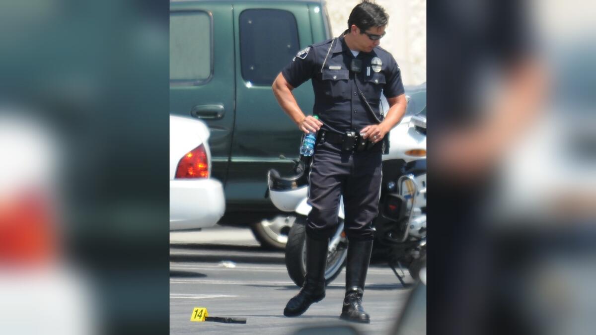 In this July 2010 file photo, a Burbank police officer stands over a gun outside the Kmart where an officer was shot by a handcuffed shoplifting suspect.