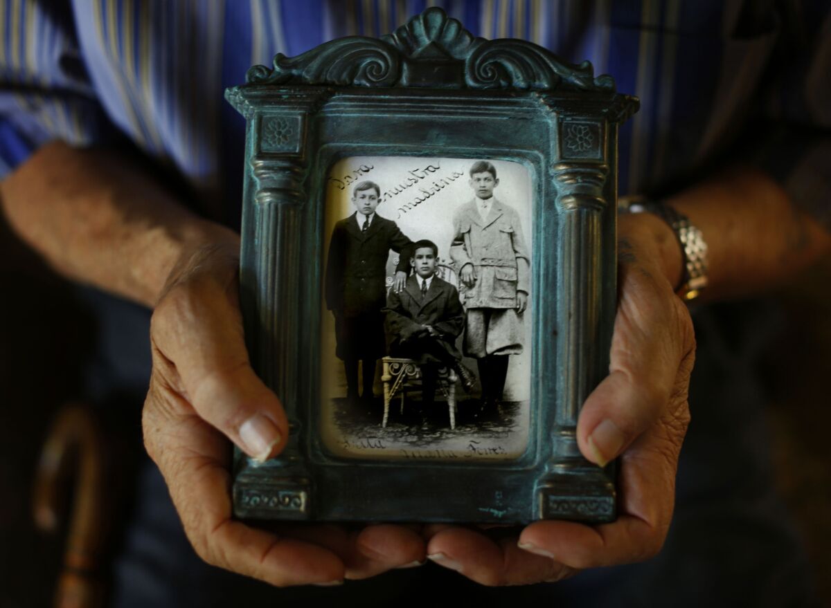 Esteban Torres, in his West Covina home, holds a photograph of his father, who is at far right.
