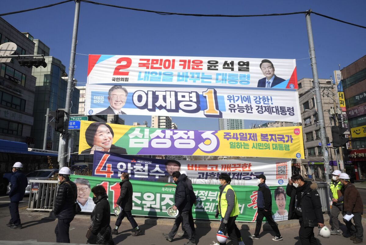 Placards featuring ruling and opposition presidential candidates hang over a street in Seoul, South Korea