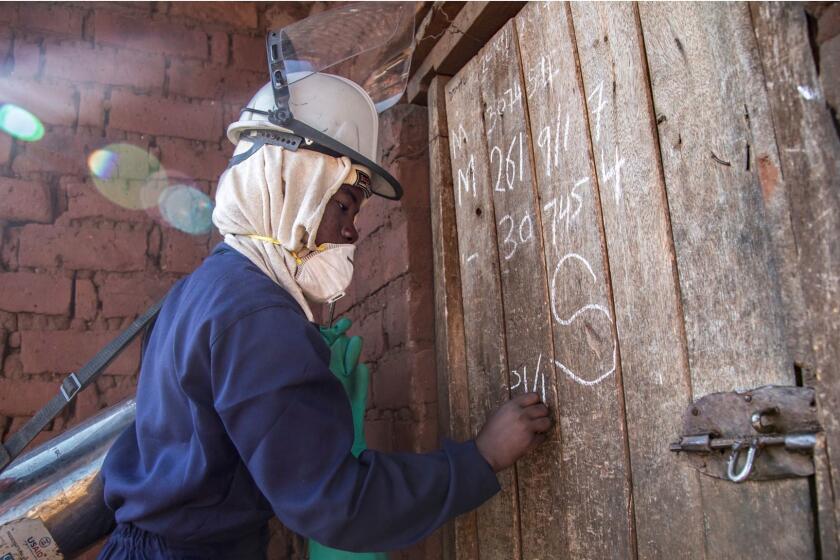 Emely Mwale, 23, is an indoor residual insecticide sprayer in the Katete District of Zambia's Eastern Province. She contracted malaria at least three times in her lifetime, and is now paid $6 a dollar battling the disease. In this photo she marks the door of house she has just finished spraying. The use of indoor residual spraying is seen as a key intervention in the fight against malaria.