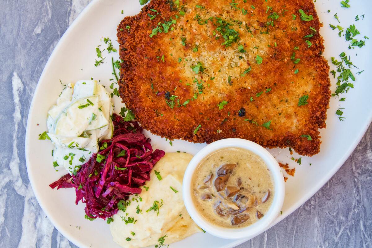 An overhead photo of chicken schnitzel with sauerkraut, parsnips, and pear salad.