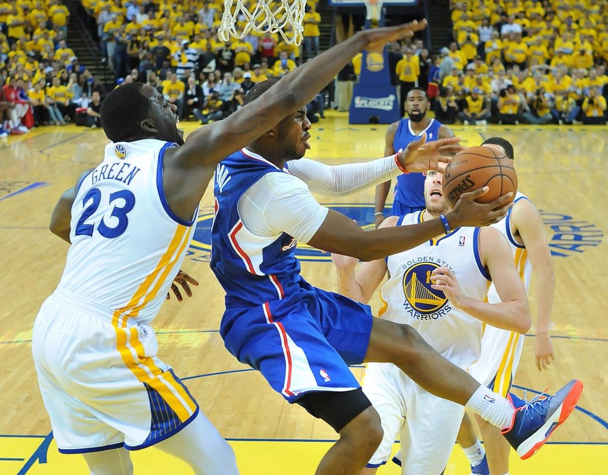 Clippers point guard Chris Paul, who finished with 15 points and 10 assists, attempts a reverse layup against Warriors power forward Draymond Green in Game 3 on Thursday night in at Oracle Arena in Oakland.