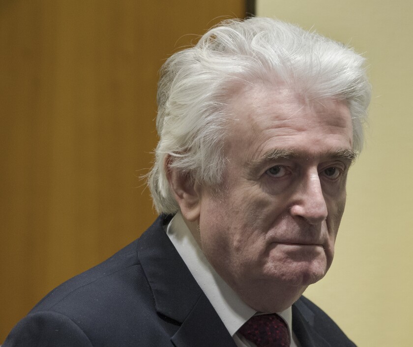 FILE - In this Wednesday, March 20, 2019 file photo, former Bosnian Serb leader Radovan Karadzic enters the court room of the International Residual Mechanism for Criminal Tribunals in The Hague, Netherlands. The British government said Wednesday, May 12, 2021 that former Bosnian Serb leader Radovan Karadzic will serve his life sentence for war crimes in a U.K. prison. Karadzic, one of the chief architects of the slaughter and devastation of Bosnia’s 1992-95 war, was convicted in 2016 by a United Nations court of genocide, crimes against humanity and war crimes. (AP Photo/Peter Dejong, file)