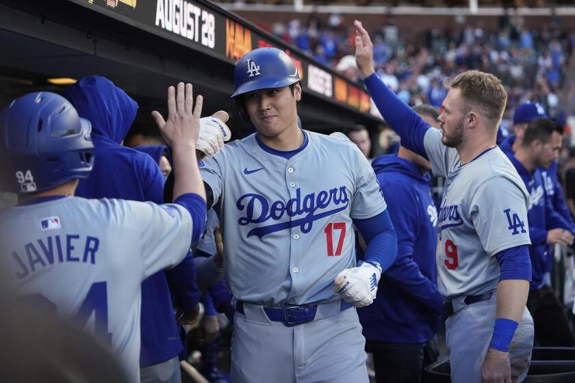 Los Angeles Dodgers' Shohei Ohtani, center, celebrates with teammates in the dugout.