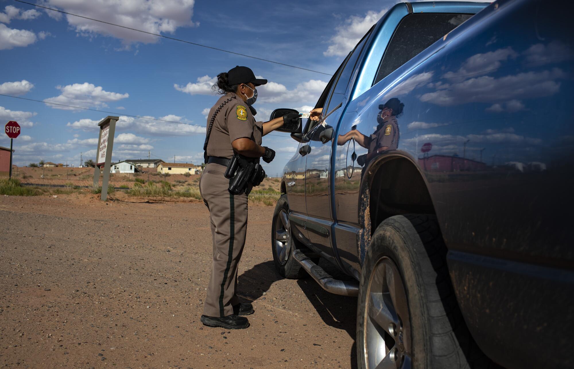Navajo Nation Officer Carolyn Tallsalt checks identification after pulling over a woman for violating a curfew