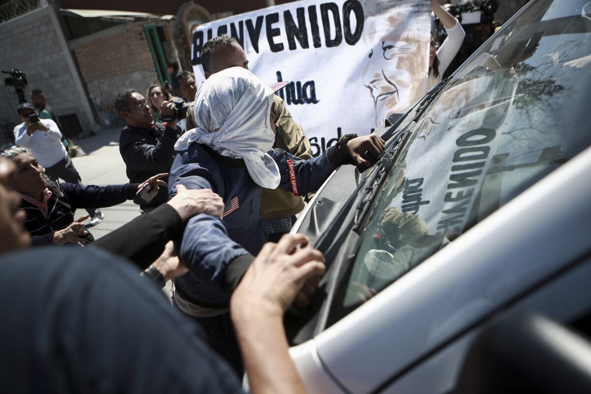 Migrantes y activistas intentan detener un vehículo en el que viaja el presidente mexicano Andrés Manuel López Obrador cuando visitaba Ciudad Juárez, en México, el viernes 31 de marzo de 2023. (AP Foto/Christian Chavez)