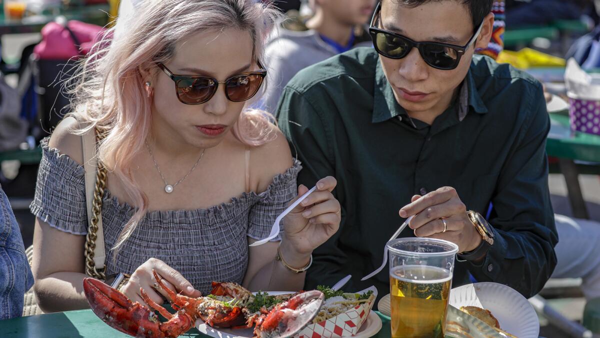 Hanh Nguyen 28, left, and husband Ryan Nguyen, 30, eat grilled lobster and noodles from Cafe 949 at the Tet Festival.