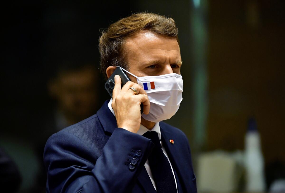 FILE - In this Monday, July 20, 2020 file photo, French President Emmanuel Macron speaks on his mobile phone during a round table meeting at an EU summit in Brussels. French newspaper Le Monde is reporting that the cellphones of French President Emmanuel Macron and 15 members of the French government in 2019 may have been among potential targets of surveillance by spyware made by the Israel-based NSO Group. The Paris prosecutor’s office announced Tuesday, July 20, 2021 it is investigating the suspected widespread use of the Pegasus spyware to target journalists, human rights activists and politicians in multiple countries. (John Thys, Pool Photo via AP, File)