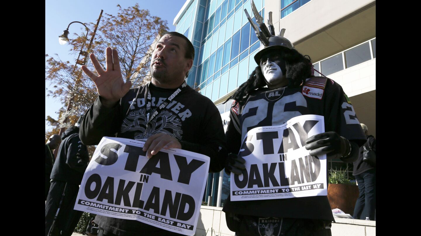 Oakland Raiders fans Griz Jones, left, and Ray Perez make their case for keeping the NFL team in Oakland with a Jan. 12 demonstration outside the hotel where NFL owners are meeting in Houston.
