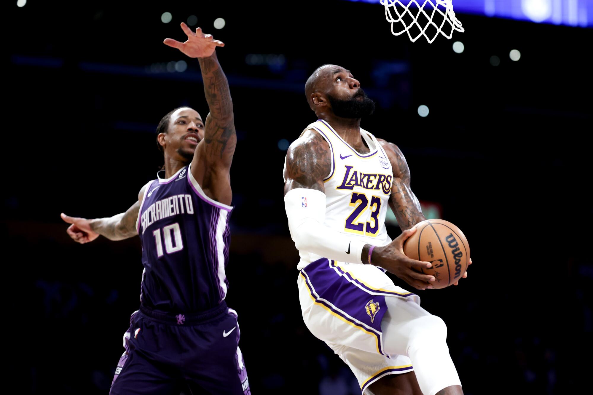 Lakers forveti LeBron James (sağda), Aralık ayındaki bir maçta ters smaç için Kings forveti DeMar DeRozan'ın yanından süzülerek geçiyor.