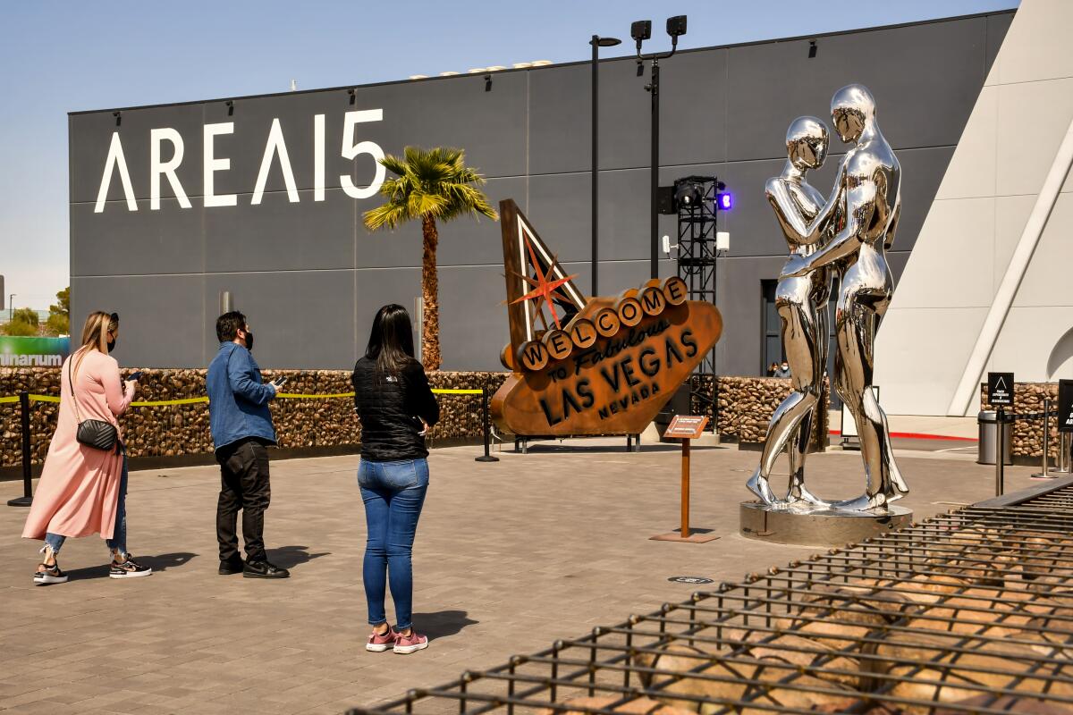 The exterior of Area 15, which features a vintage "Welcome to Las Vegas" sign and a silver sculpture of a man and woman.