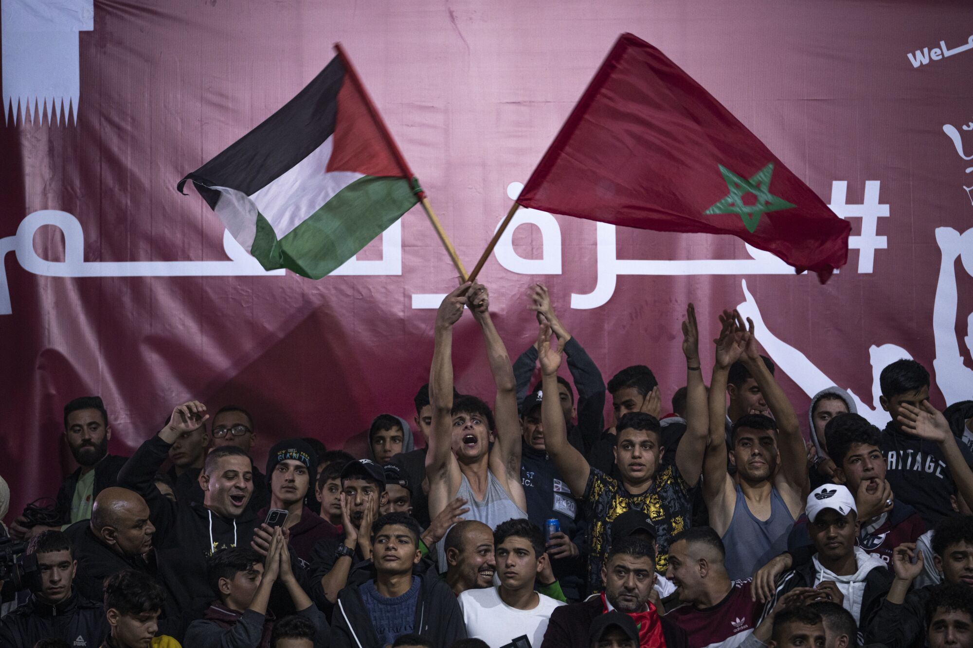 Des Palestiniens de la ville de Gaza agitent des drapeaux marocains et leurs drapeaux nationaux en regardant la retransmission en direct des quarts de finale de la Coupe du monde