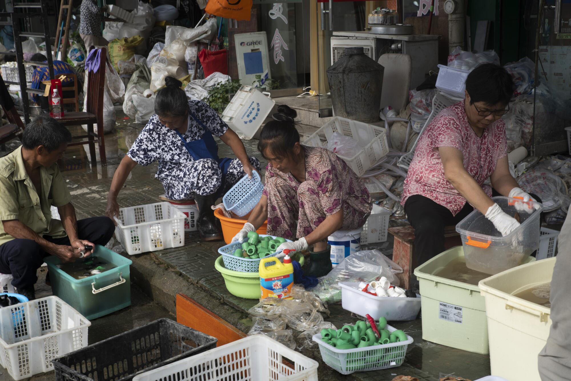 Workers at a home appliances shop try to salvage parts to sell at a discount.