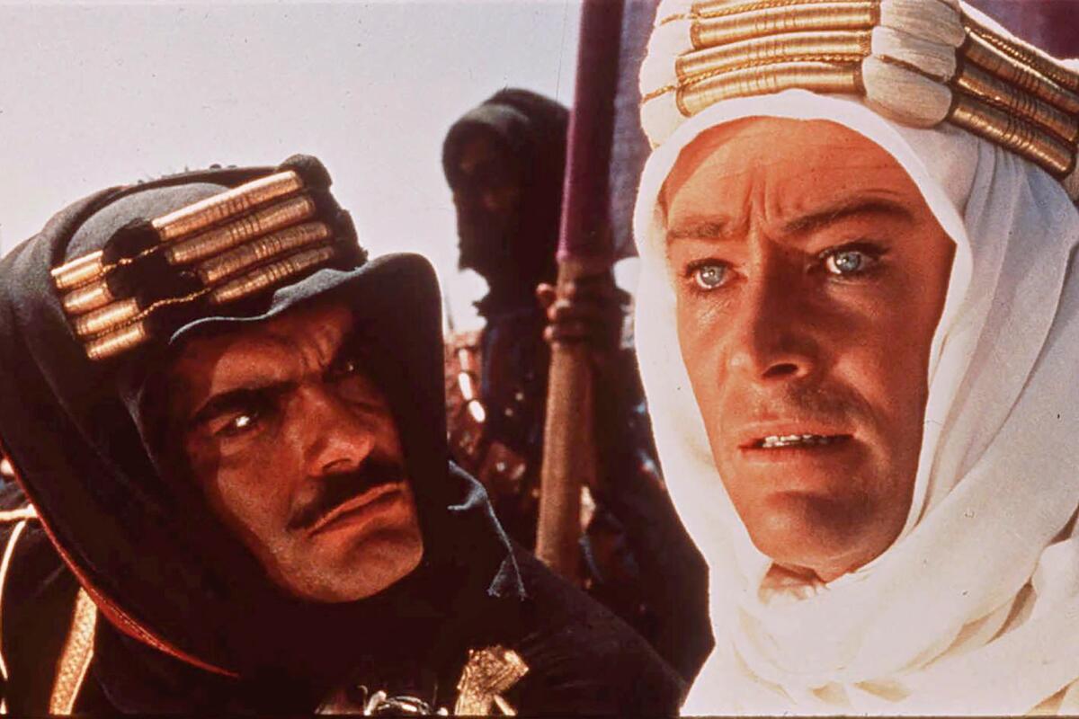 A man in a black head covering looking at a man in a white head covering.